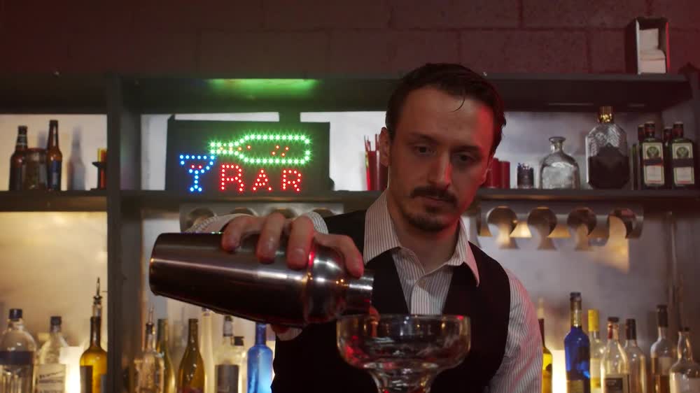 A bartender carefully pouring a cocktail